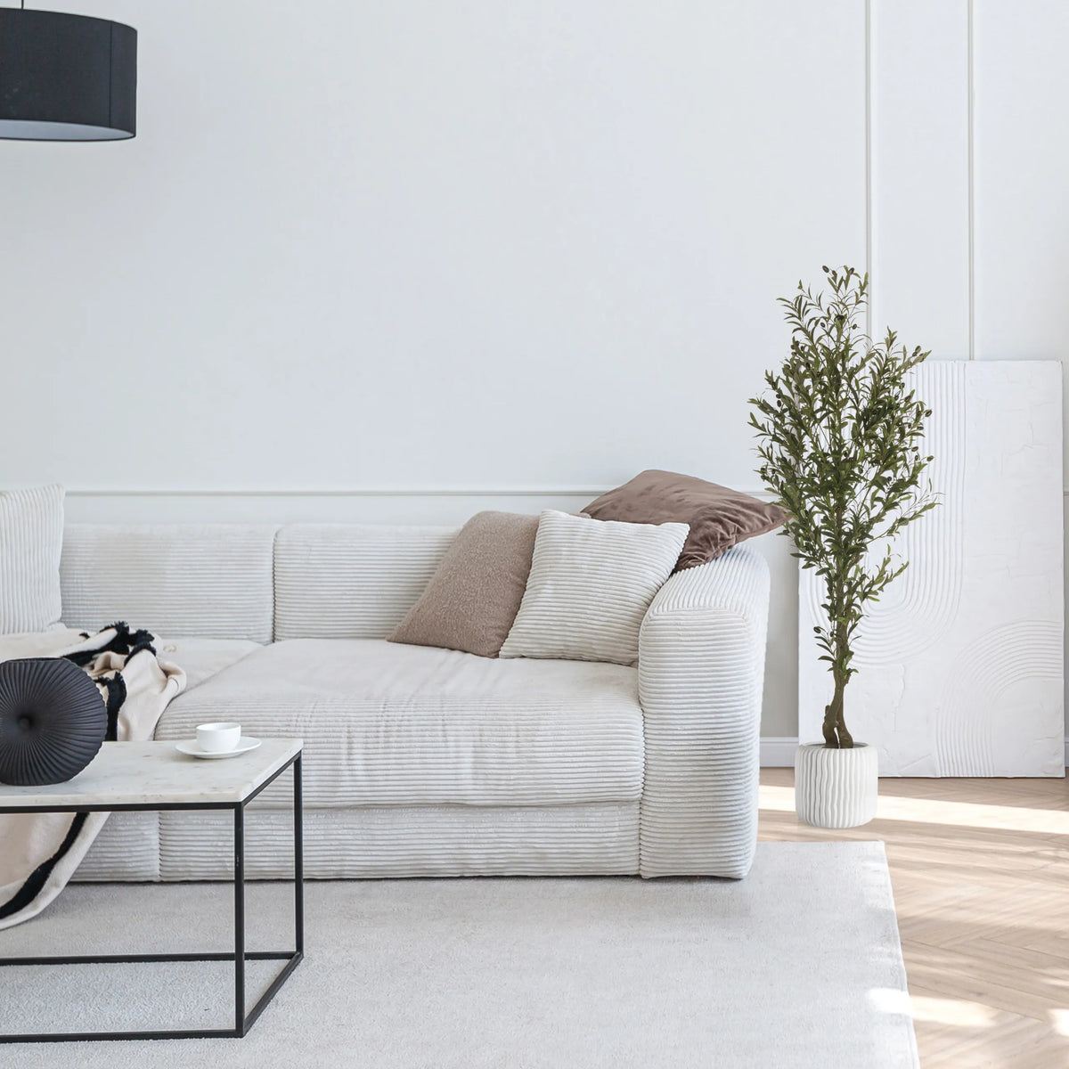 Green artificial plant OLIVE I in a white pot next to a light-coloured sofa by hjh OFFICE