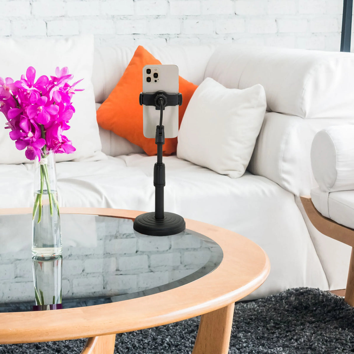 Black mobile phone & tablet holder FLEXMOBI II with smartphone on a glass table in front of a white sofa by hjh OFFICE