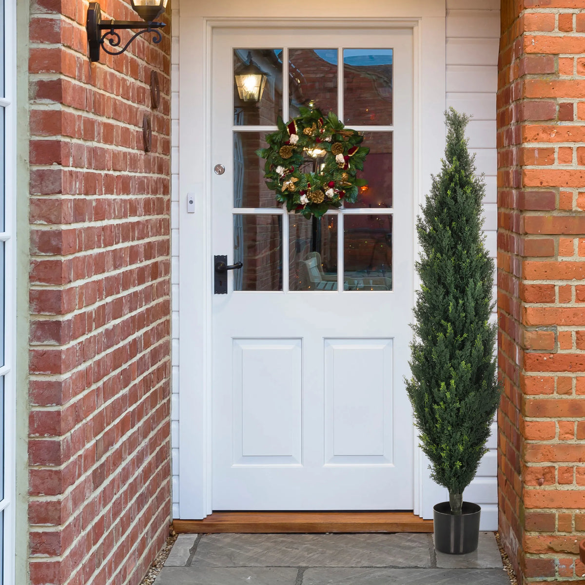 Green Artificial plant CEDRUS in a black pot next to a white front door by hjh OFFICE