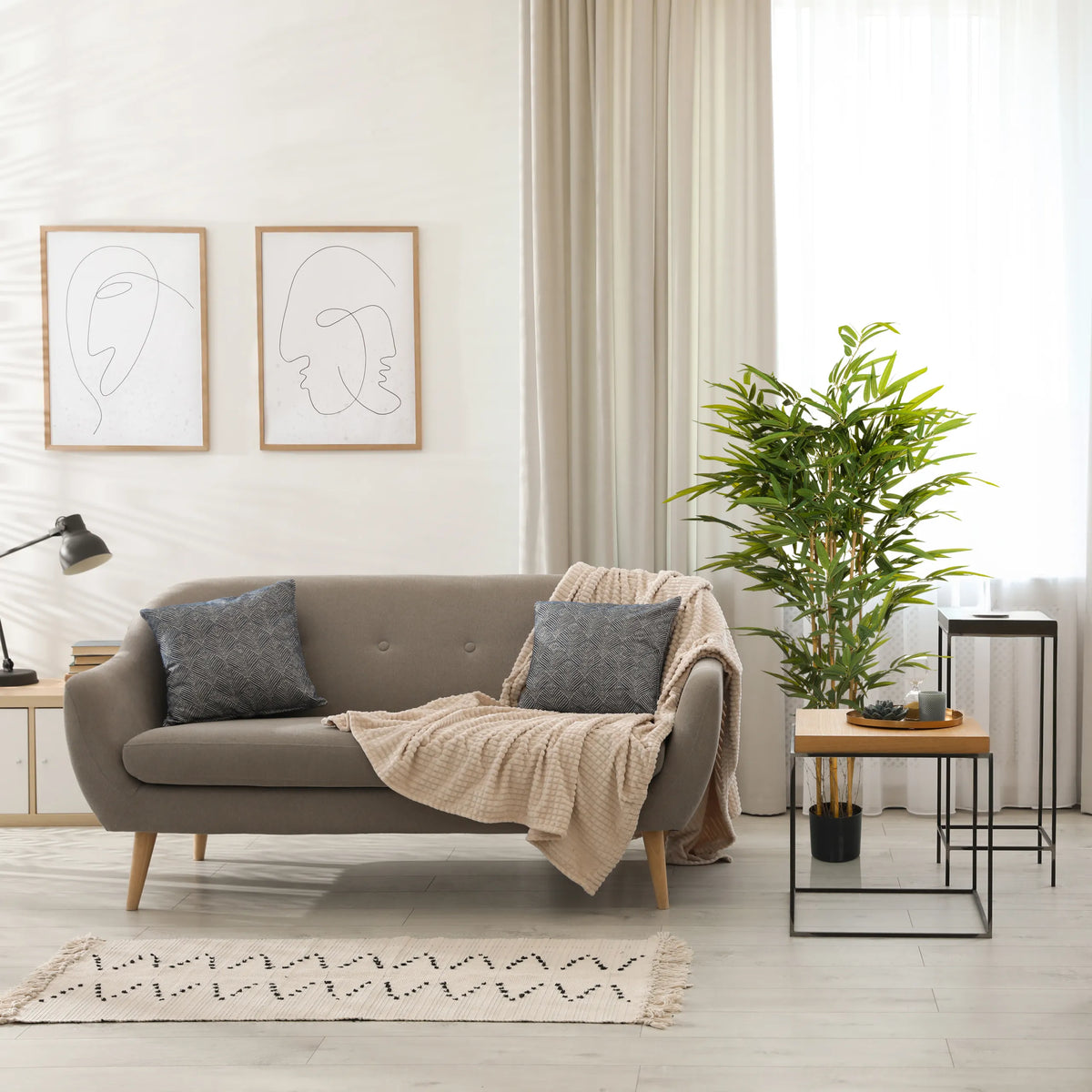 Green artificial plant BAMBUS II in a black pot next to a sofa by hjh OFFICE