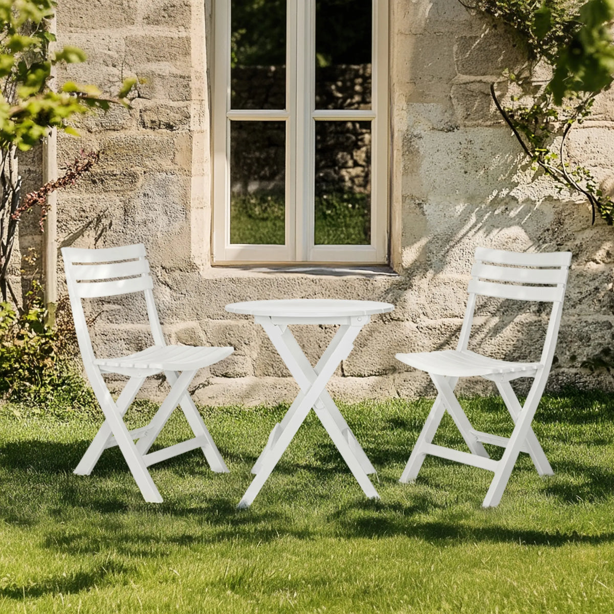 White TRAVANO T folding table with two matching folding chairs on a green lawn by hjh LIVING