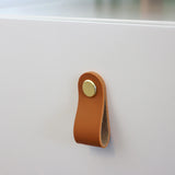 Brown leather handle with gold-coloured button on the white side table TAROLO III by hjh LIVING