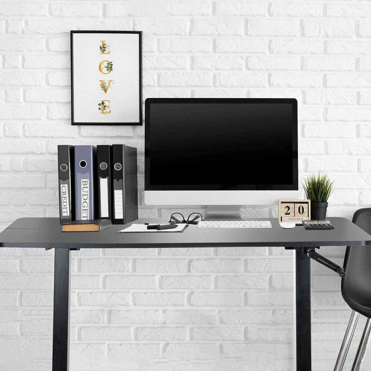 Black standing desk STAND CR with monitor, keyboard and ring binders in front of a white brick wall by hjh OFFICE