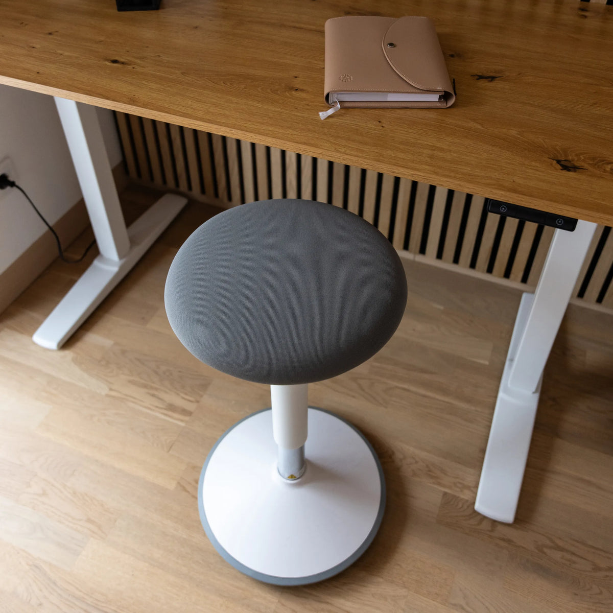Grey padded seat of the BALANCE SIT III W standing aid with a white cross base and central column by hjh OFFICE