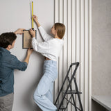 Black Folding Ladder SOLID W6 with three steps in use while hanging a picture by hjh OFFICE