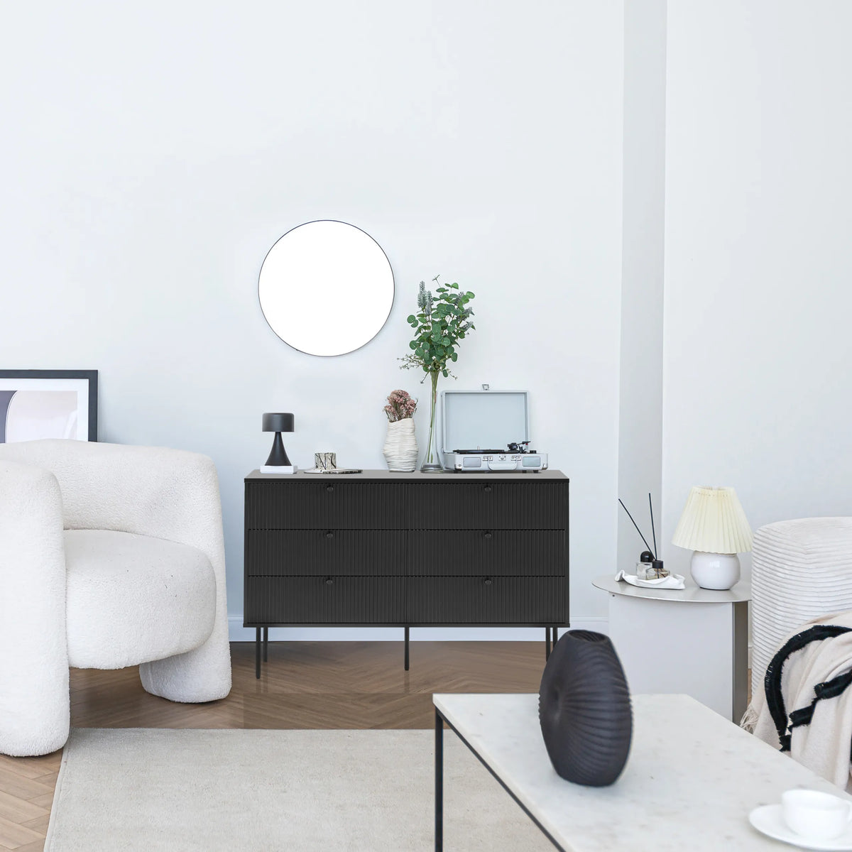 Black KARBY S sideboard with three drawers on slim legs in a modernly furnished room by hjh LIVING