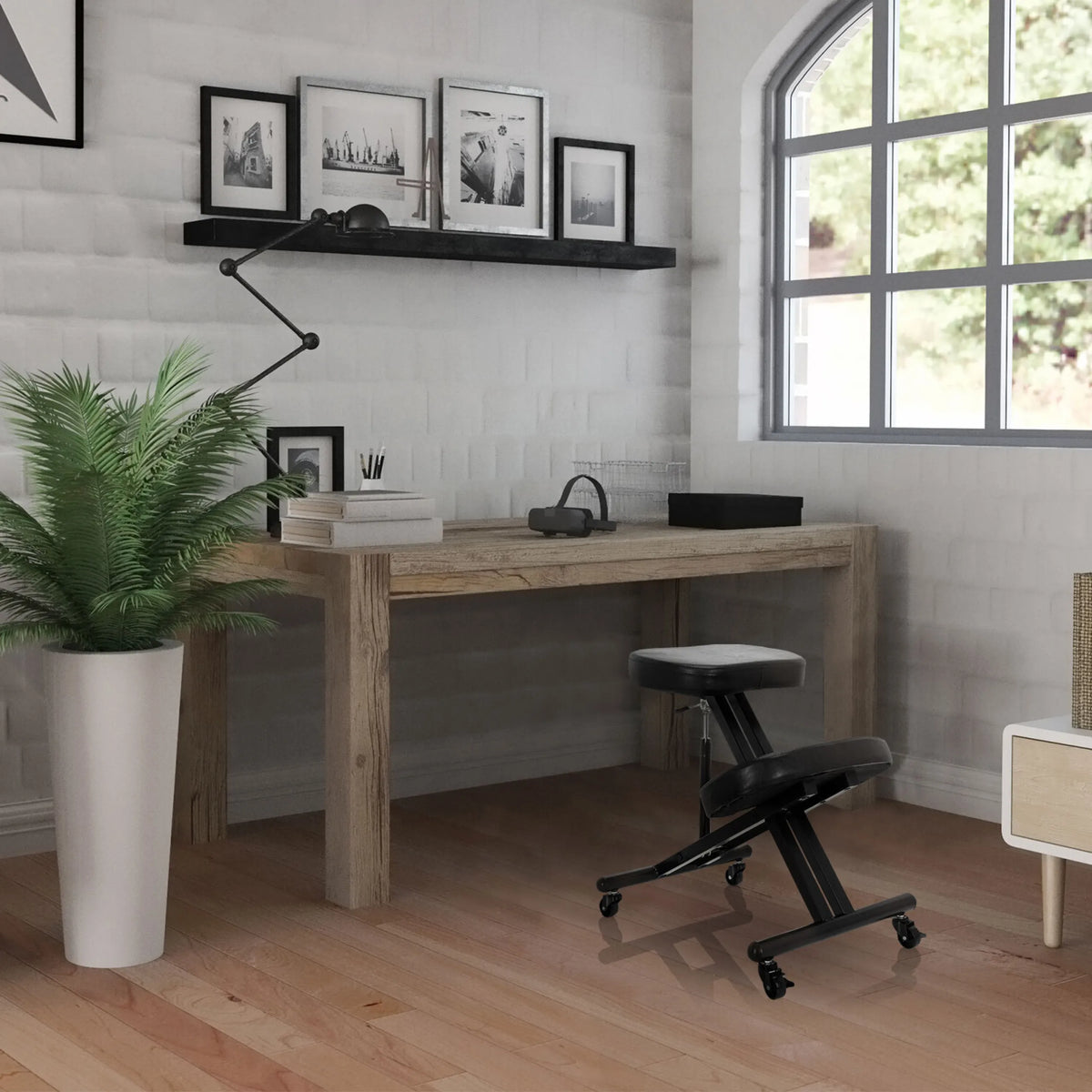 Black ORTHONI kneeling chair with castors in front of a wooden desk in a bright room by hjh OFFICE