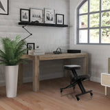 Black ORTHONI kneeling chair with castors in front of a wooden desk in a bright room by hjh OFFICE