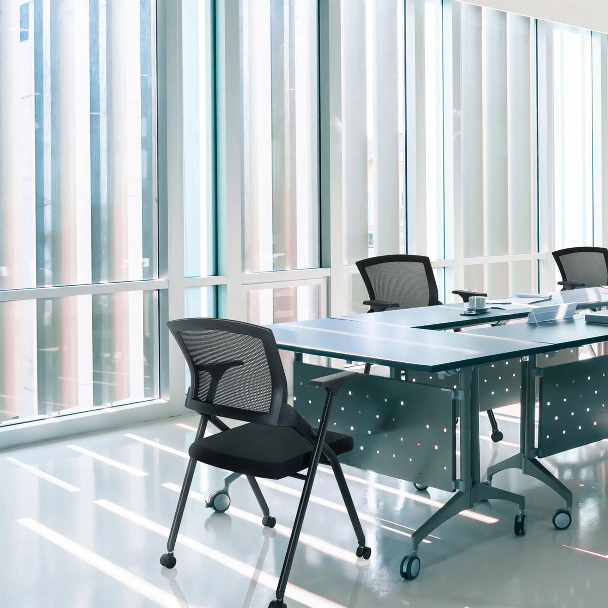 Folding chair PRIORITY II in black with mesh backrest at a conference table by hjh OFFICE