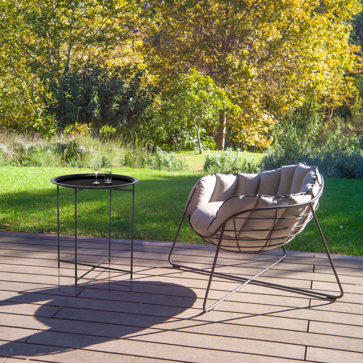 Black metal ALLRUND side table with perforated pattern on a terrace next to a lounge chair by hjh LIVING
