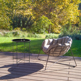 Black metal ALLRUND side table with perforated pattern on a terrace next to a lounge chair by hjh LIVING